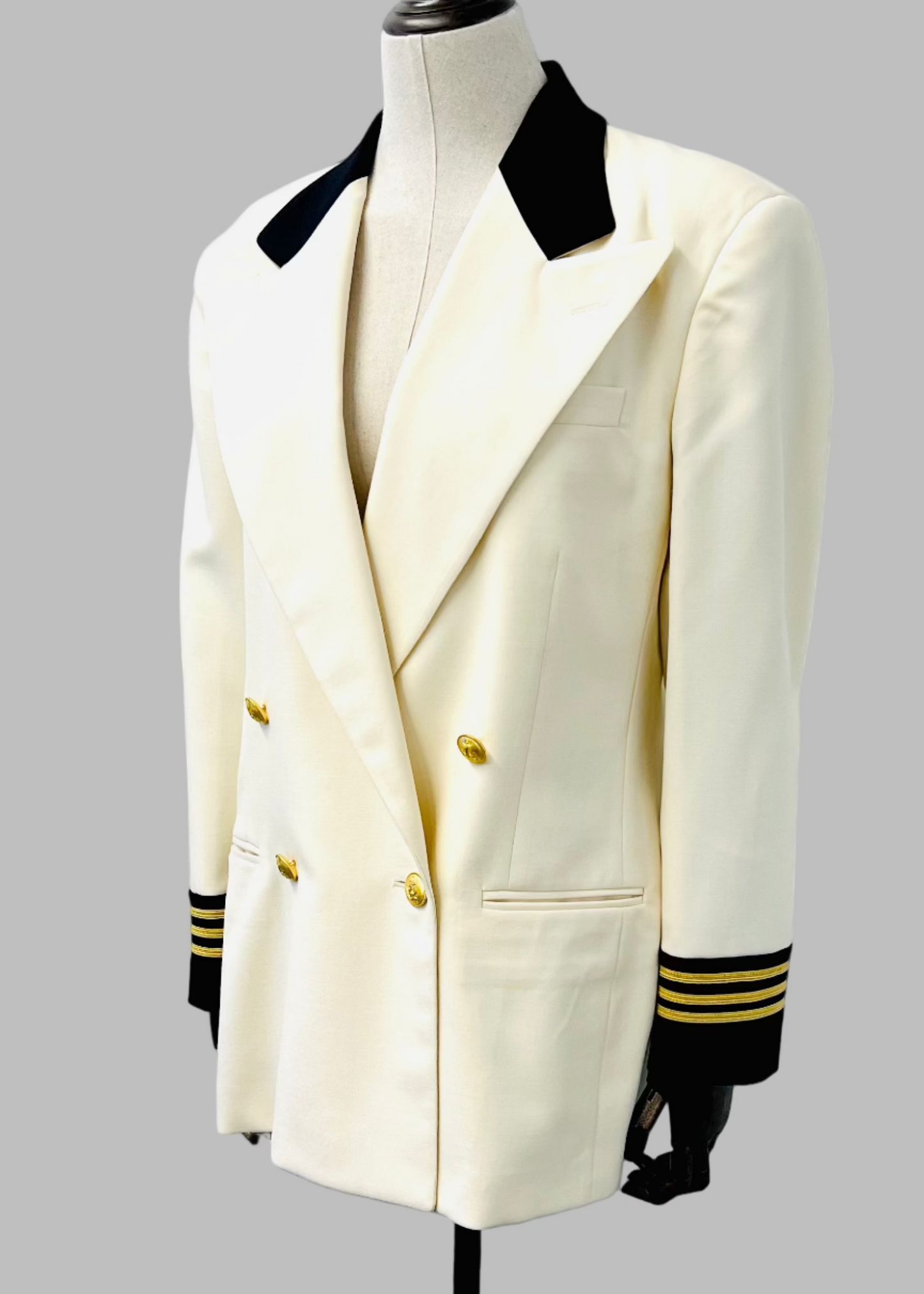 A vintage cream and black double-breasted captain's blazer with gold button and braided cord details, displayed on a mannequin against a white background.