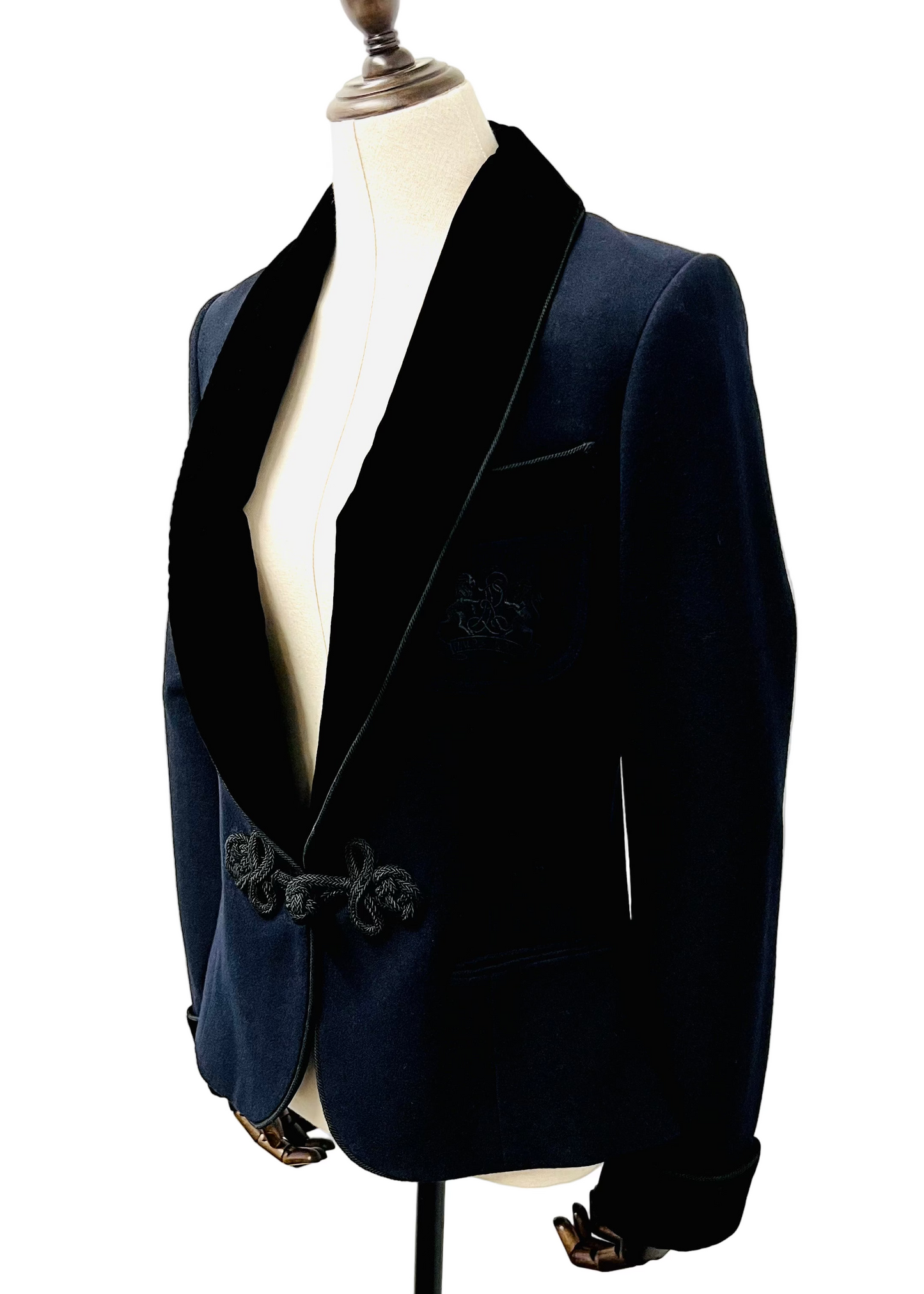 A black velvet collar dinner jacket on a mannequin, with black cording details on the jacket.