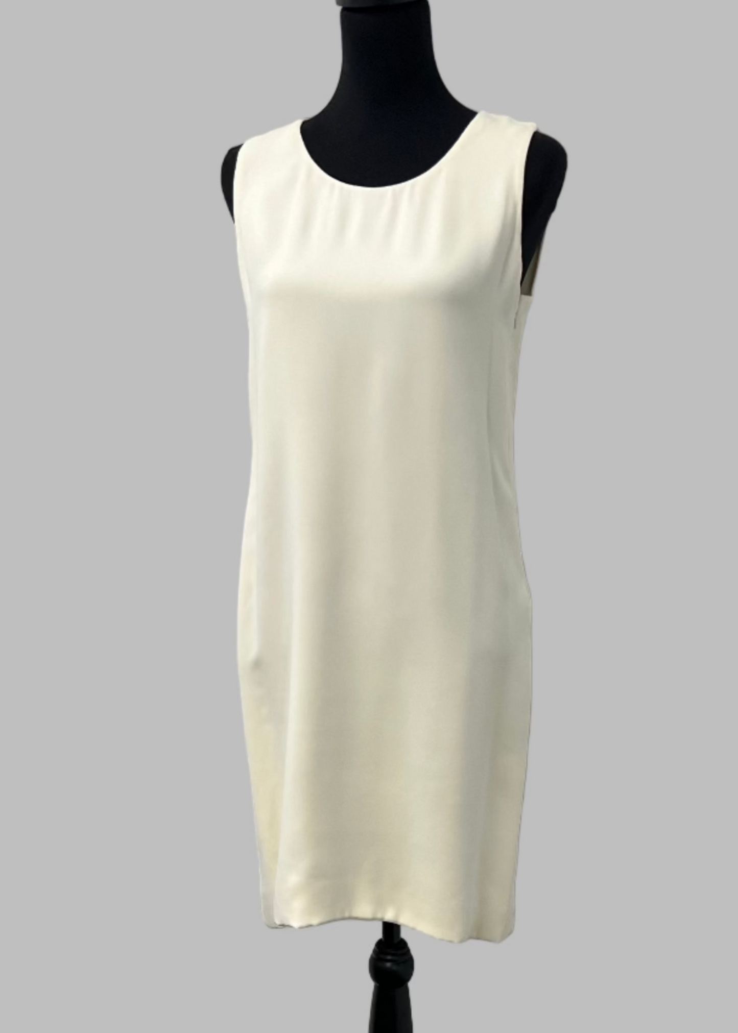 White sleeveless dress on a black mannequin against a gray background