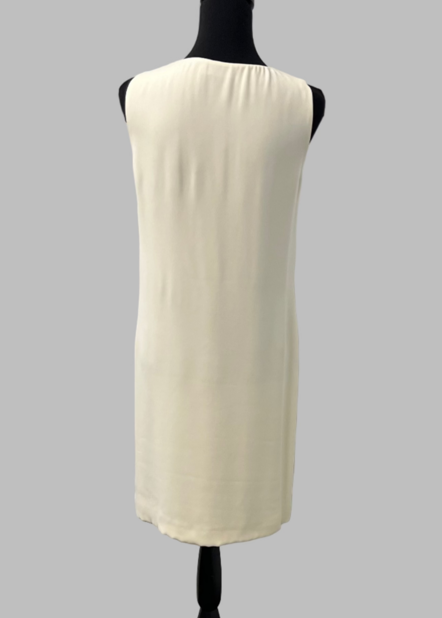 White sleeveless dress on a mannequin against a gray background