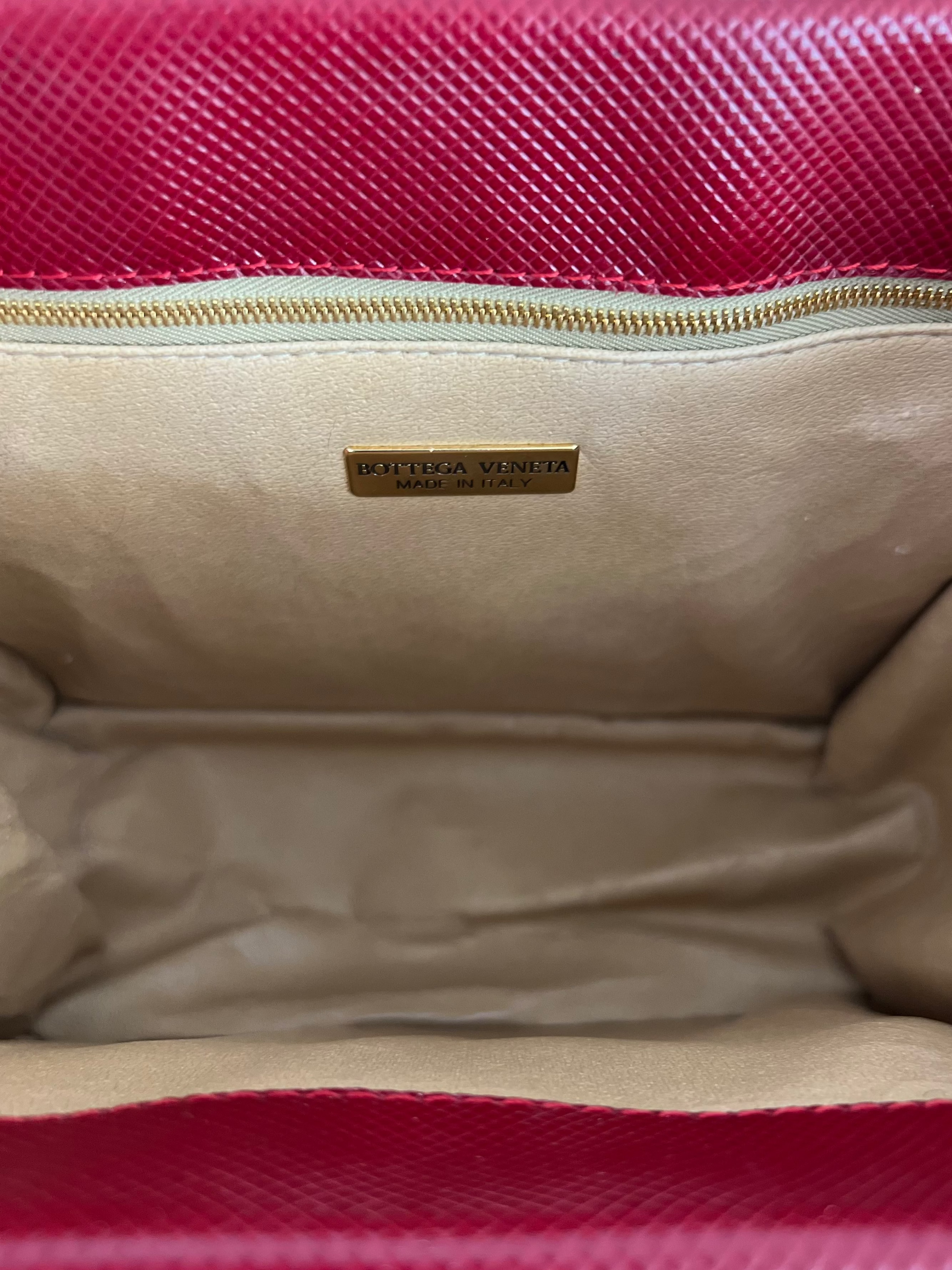 Close-up of a red handbag with a gold interior and visible brand name.